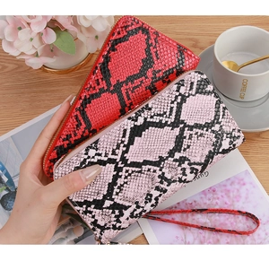 Detail of snake pattern long wallet showing the red PU leather texture and wrist strap