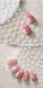 Detail of 3D embossed white cherry blossom nail stickers on pink manicure with pearls