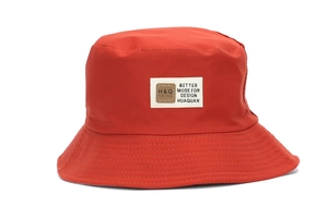 Close-up of a red sun hat featuring a white fabric patch and a brown leather logo detail