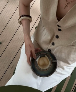 Detailed texture of khaki linen vest with black buttons and stylish resin bracelet
