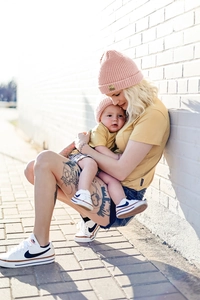 Close-up of a pink knitted baby beanie featuring a golden square patch for kids