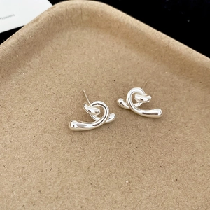 Gros plan de boucles d'oreilles clous torsadées en argent au design moderne minimaliste