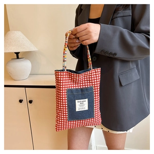 Détail du sac cabas en toile à carreaux rouges avec poche en jean et étiquette