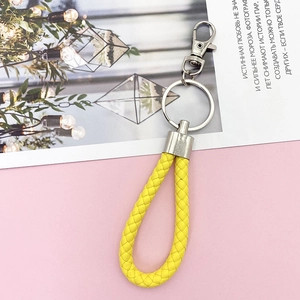 Detail view of a bright yellow braided leather keychain with silver metal ring and clasp