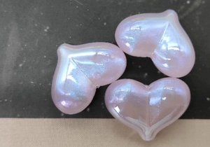 Dettaglio ravvicinato di perline rosa a forma di cuore con finitura lucida e iridescente