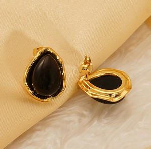 Detailed view of vintage gold water drop earrings with black stones on silk background