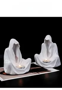 Détail de deux bougeoirs de magicien sans visage blancs posés sur un magazine