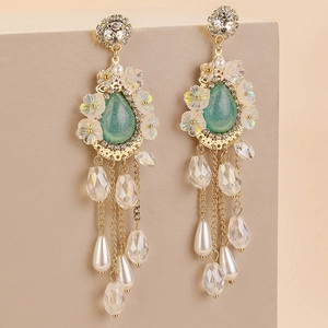 Macro detail of vintage floral tassel earrings with green crystal and pearl accents