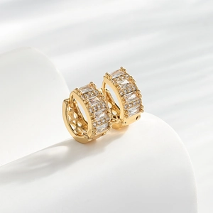 Elegant gold huggie earrings featuring baguette-cut zircon stones on a white stand