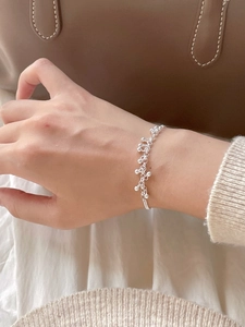 Detail of 925 sterling silver beaded bracelet worn against elegant knitwear and leather