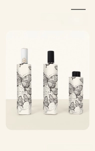 Three ivory folding umbrellas with black butterfly print showing automatic and manual options