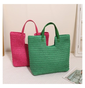 Close-up of woven straw tote bags in vibrant fuchsia and green with leather handles