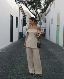 Detail of light beige off-shoulder top and wide-leg trousers in textured linen fabric