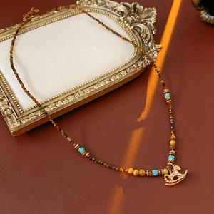 Vintage tiger eye beaded necklace featuring a golden horse pendant on a retro frame