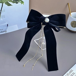 Detail of black velvet bow hair clip featuring a rose, pearl, and gold bead tassel