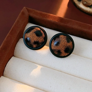 Vue macro de boucles d'oreilles léopard rondes avec base noire en boîte à bijoux