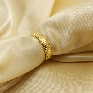 Macro detail of 18K gold stainless steel ring with vertical striped texture on satin