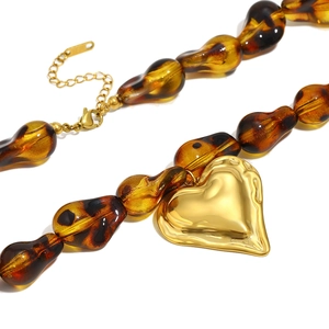 Detail of bohemian amber resin beads and large gold heart pendant necklace for women