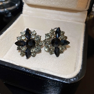 Macro shot of vintage floral stud earrings with blue rhinestones in a velvet jewelry box