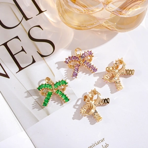 Detailed view of bow-shaped pendants with purple and green zircon in gold finish
