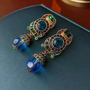 Detail of vintage palace style clip earrings with blue crystals and bronze alloy plating