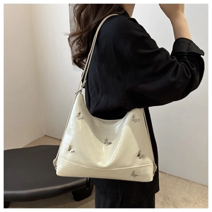Dettaglio della borsa tote bianca effetto anguilla con decorazioni a farfalla