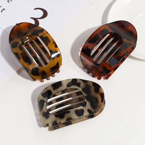 Detailed view of three leopard print hair claws in brown, auburn, and grey-brown tones