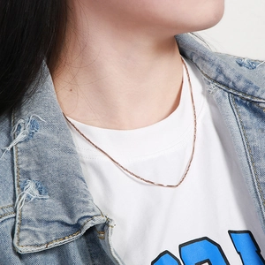 Detail shot of a slim rose gold square snake chain necklace worn by a fashion model