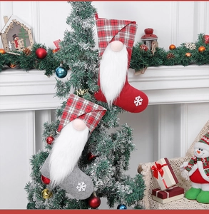 Close-up of plush Christmas gnome stockings in red and grey plaid by the fireplace