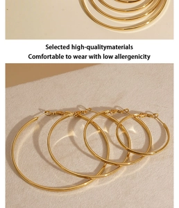 Detail of four pairs golden stainless steel hoop earrings in various sizes with polished finish