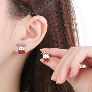 Detail of silver reindeer earrings with red enamel finish worn by a model
