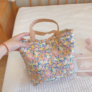 Floral cotton lunch bag with insulated lining and brown handles in a cozy home setting