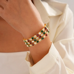 Close-up of luxury wide three-row gold bracelet with red green and white crystals