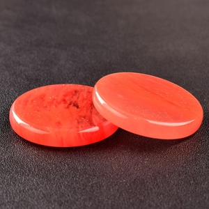 Close-up of translucent red crystal flat disc stones with smooth polished finish