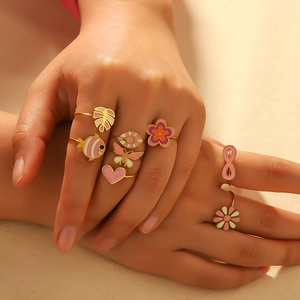 Detailed close-up of colorful enamel heart and flower rings on a model's hand