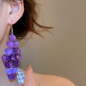 Detail view of purple geometric layered shell earrings worn on a model for beach style