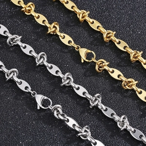 Titanium steel knotted chain necklace in gold and silver finish on textured black surface