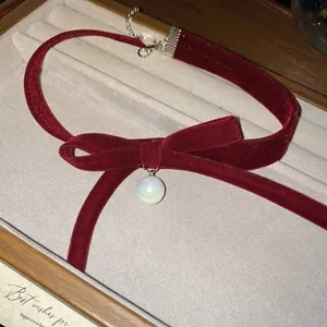Elegant red velvet bow choker necklace with a pearl pendant and silver adjustable chain
