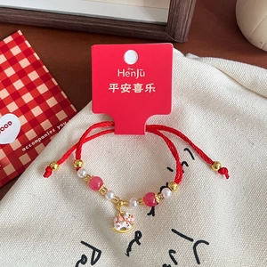 Detail of red braided bracelet with pink glass beads and white enamel pony charm