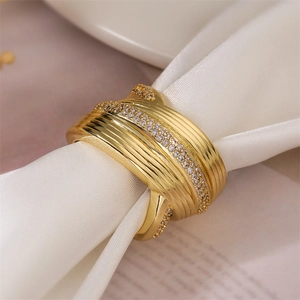 Detailansicht eines goldfarbenen Wickelrings mit Zirkonia auf einer weißen Serviette