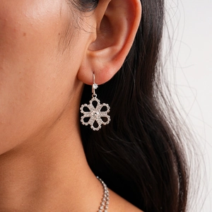 Close-up of silver floral earrings with sparkling cubic zirconia on female model
