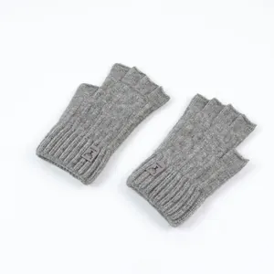 Detail of grey knitted fingerless gloves with ribbed texture and deer head logo patch