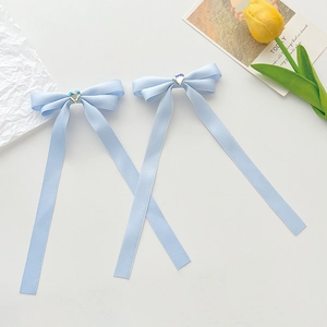 Pair of light blue ribbon bow hair clips with heart accents on a clean white surface