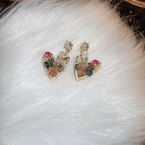 Macro detail of luxury heart earrings with colorful crystals on soft white faux fur