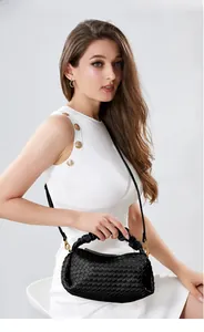 Detail of black woven leather handbag with ruffled handle and elegant gold hardware