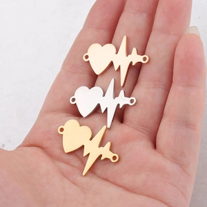 Polished stainless steel heartbeat pendants in gold and silver finish on palm