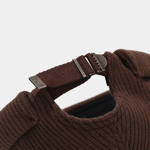 Detail of vintage metal adjustment buckle on a brown ribbed knit dock worker cap