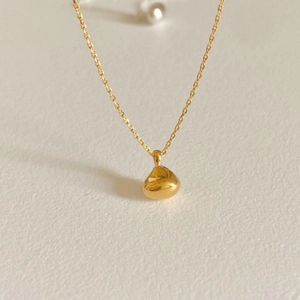 Minimalist 925 sterling silver necklace with gold droplet pendant on a beige surface