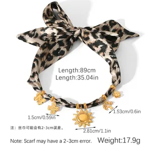Detailed view of leopard print ribbon necklace with golden cross and tree charms