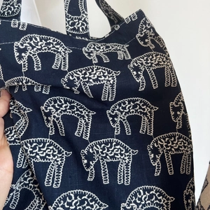 Detailed close-up of white sheep embroidery on navy blue canvas tote bag fabric